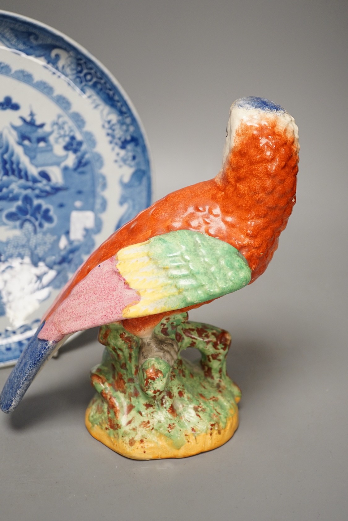 A Staffordshire pottery figure of a parrot, 19.5cm tall, together with a blue and white dish